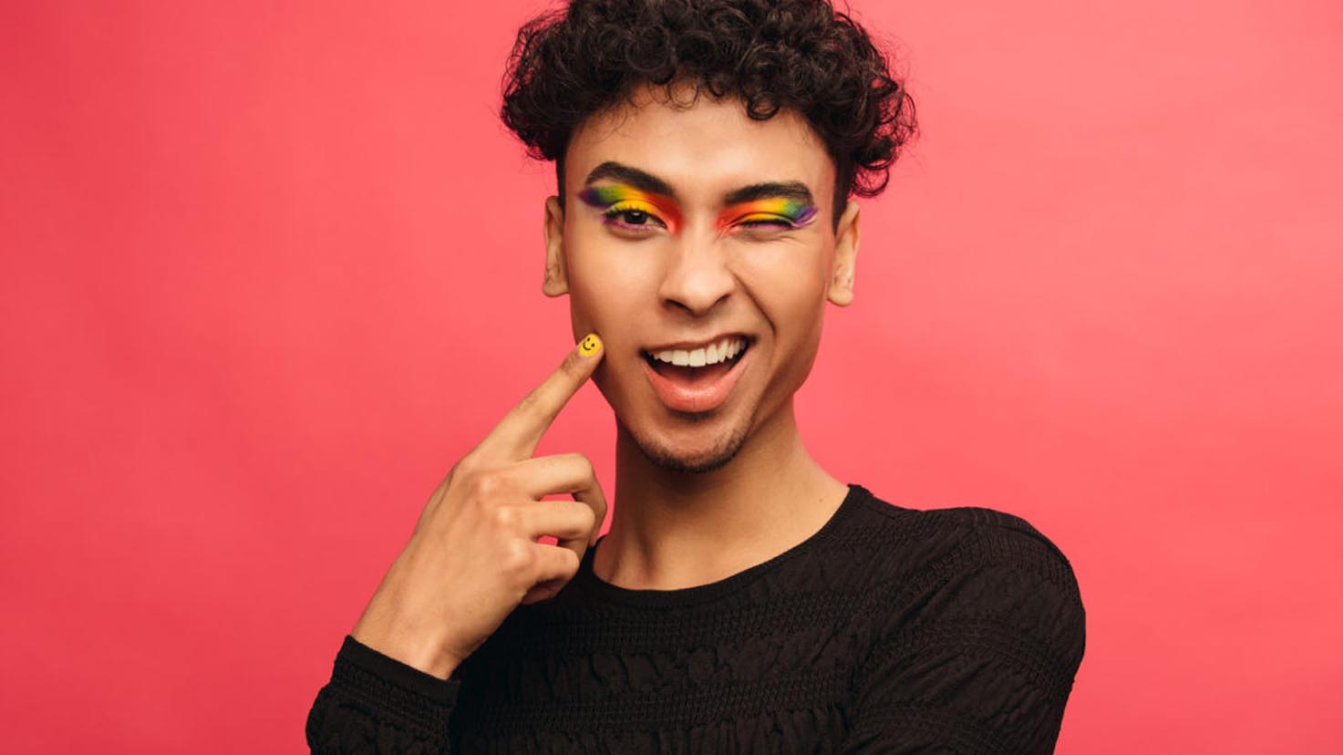 Gay man with rainbow eyeshadow winking at camera
